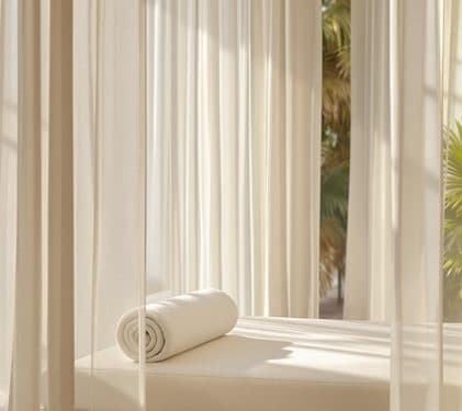 A treatment bed by a sunlit, curtained window.